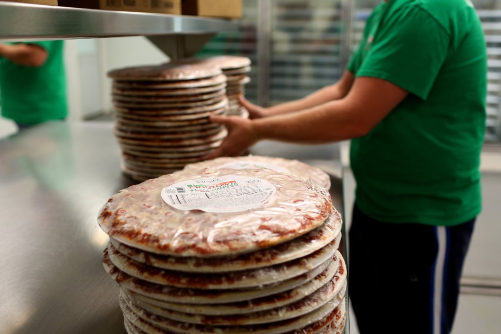 an employee wraps a frozen pizza.